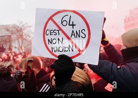 Frankreich / Paris / 07/03/2023, Jan Schmidt-Whitley/Le Pictorium - Demonstration gegen die Rentenreform in Paris - 7/3/2023 - Frankreich / Paris / Paris - Ein Demonstrante trägt ein Schild mit der Aufschrift "64 ist kein Macron". Selbst wenn die Zahl der Streikenden nicht die Werte für Januar erreichte, begrüßten die Gewerkschaften am Dienstag, dem 7. März, eine "historische Mobilisierung" während der Demonstrationen, bei denen laut dem Innenministerium 1,28 Millionen Menschen in Frankreich und laut der CGT 3,5 Millionen Menschen zusammenkamen. Stockfoto