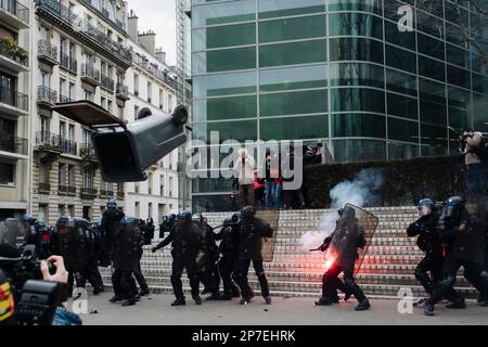 Frankreich / Paris / 07/03/2023, Jan Schmidt-Whitley/Le Pictorium - Demonstration gegen die Rentenreform in Paris - 7/3/2023 - Frankreich / Paris / Paris - Demonstranten werfen einen Mülleimer auf eine Gruppe von Polizeibeamten. Selbst wenn die Zahl der Streikenden nicht die Werte für Januar erreichte, begrüßten die Gewerkschaften am Dienstag, dem 7. März, eine "historische Mobilisierung" während der Demonstrationen, bei denen laut dem Innenministerium 1,28 Millionen Menschen in Frankreich und laut der CGT 3,5 Millionen Menschen zusammenkamen. Stockfoto