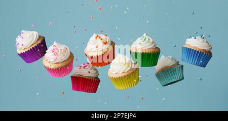 Banner mit einer Reihe von bunten Regenbogen-Cupcakes mit herabfallenden Zuckerstreuseln Stockfoto