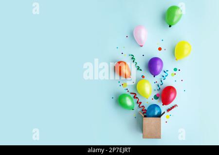 Die Geburtstagsparty lag mit bunten Ballons und Konfetti, die aus einer Geschenkbox flohen Stockfoto