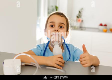 Kleines Mädchen in einer Maske für Inhalationen, Inhalation mit Vernebler zu Hause Inhalator auf dem Tisch, innen, krankes Kind Stockfoto