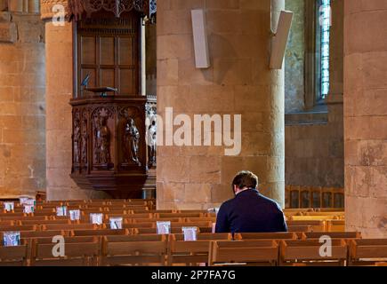 Ein Mann sitzt auf der Bank, im Inneren von Southwell Minster, Southwell, Nottinghamshire, England, Großbritannien Stockfoto