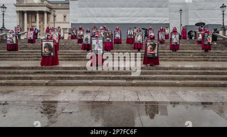 Britisch-iranische Demonstranten, gekleidet wie Figuren aus dem Magazin der Magd am Trafalgar Square am Internationalen Frauentag 2023. Stockfoto