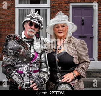 Portrait eines stilvollen, futuristischen Steampunk-Paares mittleren Alters, das vor einem Haus steht. Stockfoto