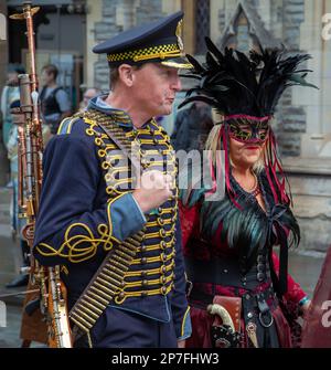 Ein männlicher und weiblicher Steampunk. Der Mann trägt eine Militäruniform und eine Waffe. Die Frau trägt einen Federkopfschmuck und eine Maske. Stockfoto