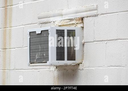 Horizontaler Schuss eines zerschmetterten Klimaanlagenfensters in einer Betonwand. Stockfoto