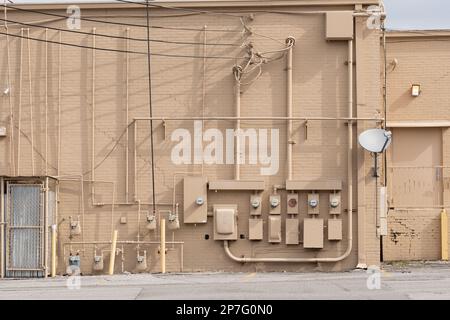 Horizontale Aufnahme eines verfallenen alten Einkaufszentrums mit elektrischen Zählern an einer Außenwand. Stockfoto