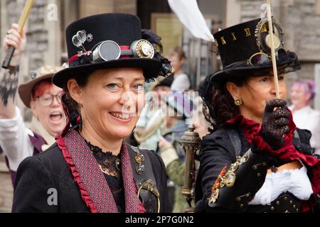 Eine Gruppe weiblicher Steampunks, die in einer Prozession entlang einer Straße laufen. Stockfoto