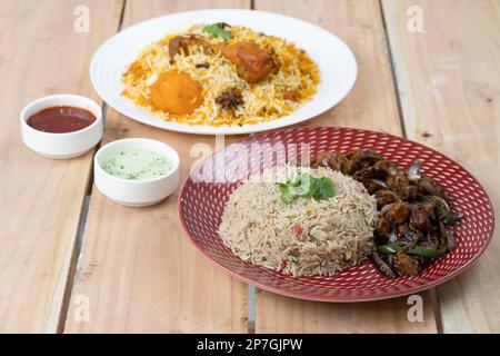 Chicken Dry Chili mit einer Schüssel gebratenen Reis zusammen mit Biryani und Saucen auf strukturiertem Hintergrund Stockfoto