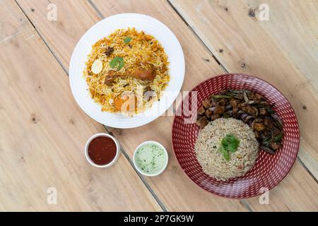 Chicken Dry Chili mit einer Schüssel gebratenen Reis zusammen mit Biryani und Saucen auf strukturiertem Hintergrund Stockfoto