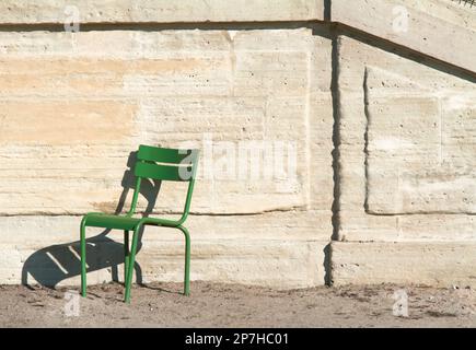 Ein leerer grüner Stuhl gegen Eine Steinmauer in den Jardin Tuilerien, Paris, Frankreich Stockfoto