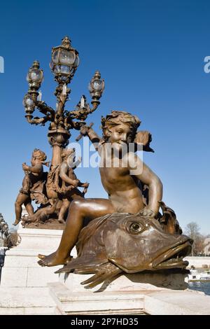 Statuen auf der Pont Alexandre III mit der Genie au Trident Statue einer Cherub auf Einem Fisch, Paris Frankreich Stockfoto