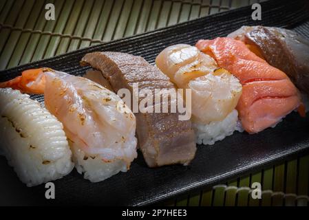Japanisches Temaki-Sushi mit Garnelen, Thunfisch, Tintenfisch, Tintenfisch auf schwarzem Teller, asiatischem Essen, traditionellem japanischem Essen Stockfoto