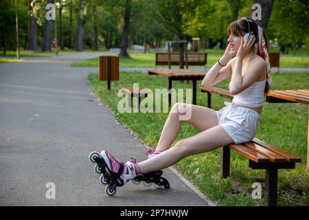 Mädchen hört Musik über Kopfhörer im Park Stockfoto