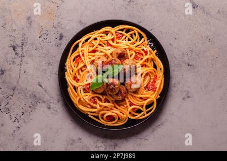 Spaghetti mit Fleischbällchen und Tomatensauce auf Steinhintergrund, Draufsicht Stockfoto