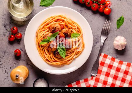 Spaghetti mit Fleischbällchen und Tomatensauce auf Steinhintergrund, Draufsicht Stockfoto