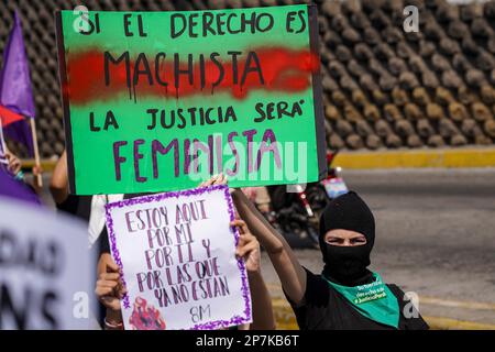 San Salvador, El Salvador. 08. März 2023. "Wenn Gerechtigkeit das Reich der Machos ist, wird Gerechtigkeit das Reich der Frauen sein", liest das Poster eines Kapuzenaktivisten während einer Kundgebung zum Internationalen Frauentag. Kredit: Camilo Freedman/dpa/Alamy Live News Stockfoto