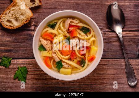 Hühnersuppe mit Nudeln und Gemüse in einer weißen Schüssel Stockfoto