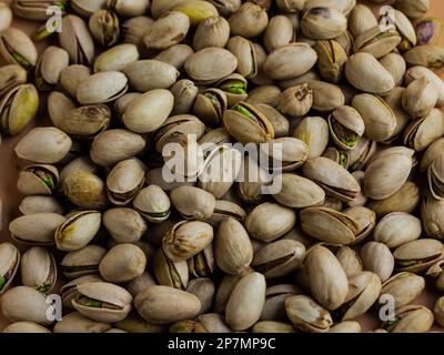 Pistaziennüsse in der Schale mit cremefarbenem Hintergrund Stockfoto