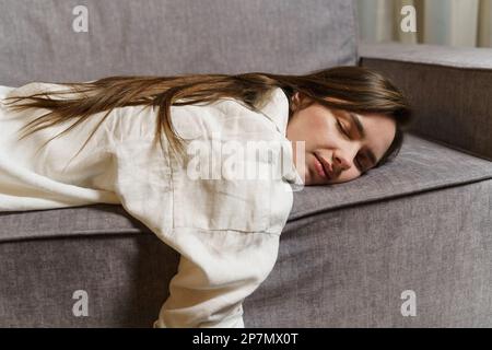 Junge, schöne Geschäftsfrau liegt nach der Arbeit auf der Couch, schläft, ruht sich aus. Stockfoto