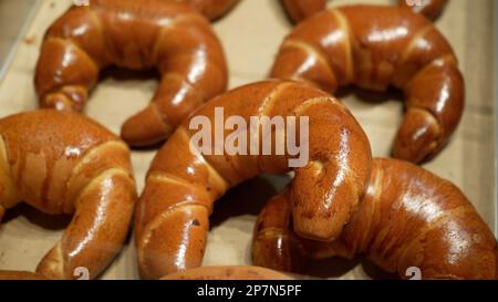 Reihen von warmen, frisch gebackenen Brötchen im Bäckereistand im örtlichen Lebensmittelgeschäft Stockfoto
