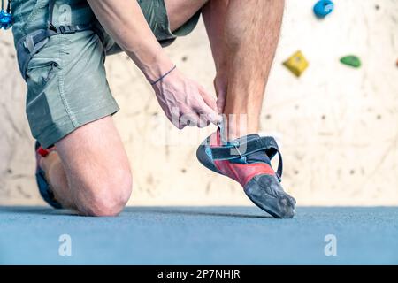 Kletterschuhe neben der Kletterwand anziehen Stockfoto