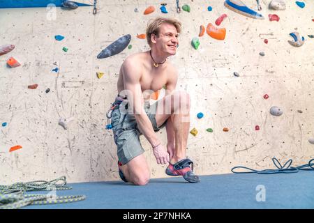 Kletterschuhe neben der Kletterwand anziehen Stockfoto