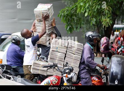 Zwei Männer entladen Zeitungen, die mit dem Motorrad in Arusha (Tansania) geliefert werden. Stockfoto