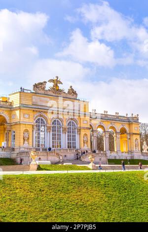 Wien, Aussia - 3. April 2015: Die Gloriette im Schlossgarten Schönbrunn vor dem wolkigen blauen Himmel. Touristen, die herumlaufen. Stockfoto