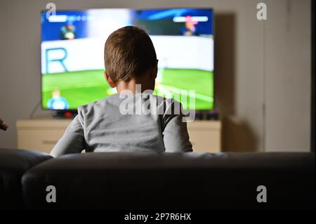 Ein Junge sitzt auf dem Sofa und sieht zu Hause Fußball im fernsehen Stockfoto