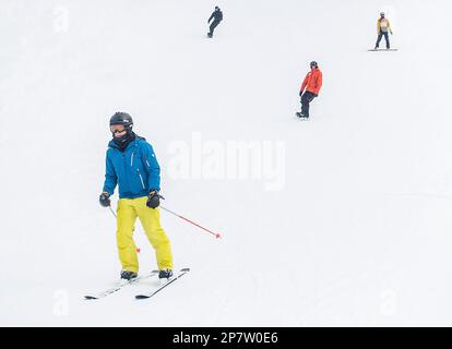 Skifahrer und Snowboarder auf Pisten Stockfoto