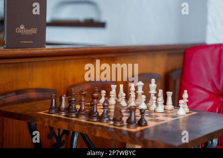 Weiße und braune Schachfiguren aus Holz auf dem Schachbrett im alpinen Hotel Stockfoto