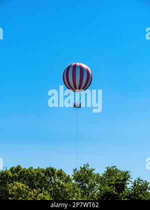 Rot-weiß gestreifter Heißluftballon über den Bäumen im Budapester Stadtpark Ungarns Stockfoto