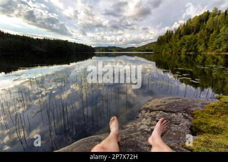 Ein Mann ruht sich an einem malerischen See nach einer Wanderung entlang des High Coast Trail (Högakustenleden) in Schweden aus Stockfoto