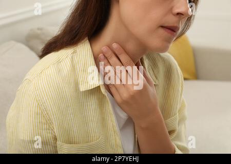 Reife Frau, die sich in geschlossenen Räumen einer Schilddrüsen-Selbstuntersuchung unterzieht, Nahaufnahme Stockfoto