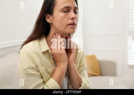 Reife Frau, die zu Hause eine Schilddrüsen-Selbstuntersuchung macht Stockfoto