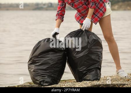 Frau mit Müllsäcken voll Müll am Strand, Schließung Stockfoto