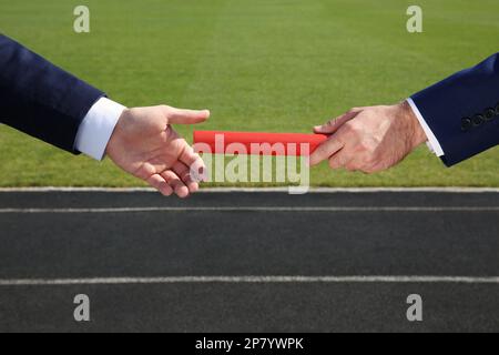 Geschäftsmann, der seinen Partner draußen mit Stab versorgt, Nahaufnahme Stockfoto