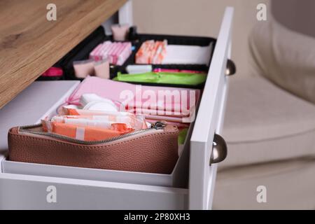 Offene Schublade mit Menstruationseinlagen und Tampons im Raum, Nahaufnahme Stockfoto