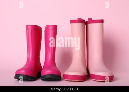 Zwei Paar Gummistiefel auf pinkfarbenem Hintergrund Stockfoto