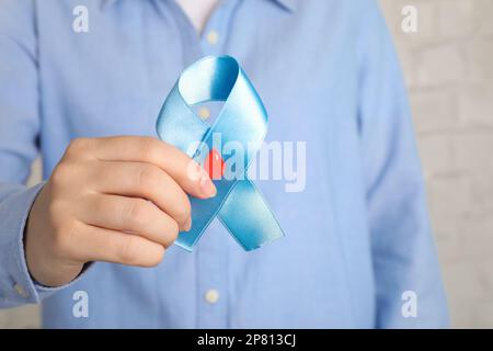 Eine Frau mit einem hellblauen Band und einem Papierbluttropfen, Nahaufnahme. Weltdiabetestag Stockfoto