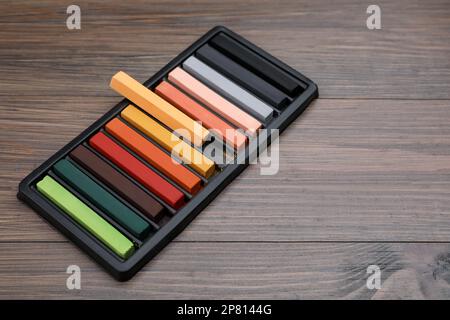 Farbenfrohe Pastelltöne im Tablett auf einem Holztisch, Platz für Text. Zeichenmaterialien Stockfoto