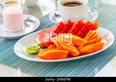 Wunderschöne geschnittene Früchte auf weißem Teller auf dem Esstisch am Morgen, künstlerischer thailändischer Stil für Obstdekoration, gesunde thailändische Früchte, Wassermelone, Papaya. Stockfoto