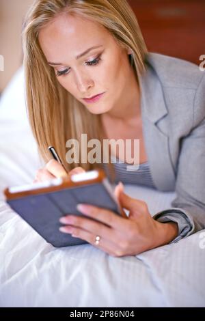 Diese organisatorischen Fähigkeiten sinnvoll einsetzen. Eine junge Geschäftsfrau, die ein digitales Tablet im Schlafzimmer benutzt. Stockfoto