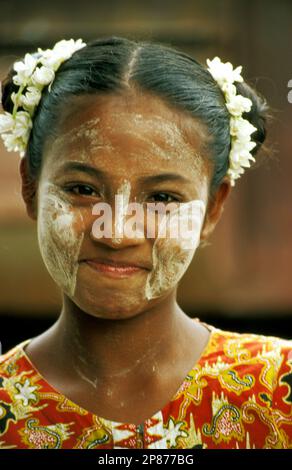 Junge burmesische Frau, die eine thanaka-Paste-Maske und einen Blumenkranz trägt, in Rangun (Yangon), Myanmar Stockfoto