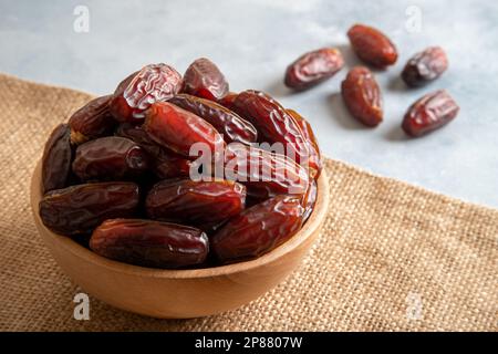 Date fruits in wooden bowl on bright background,closeup Stockfoto