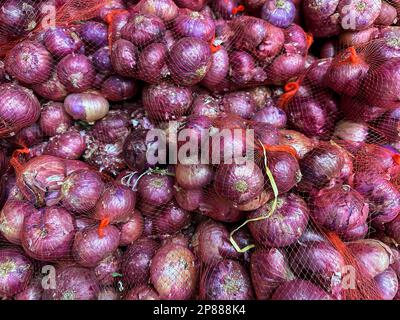 Kleine indische Zwiebeln oder rote indische Zwiebeln zum Verkauf auf einem Markt für frische Lebensmittel in Indien. Draufsicht von Roten Zwiebeln oder violetten Zwiebeln Stockfoto