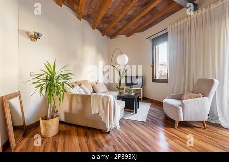 Schönes Design stilvolles Wohnzimmer mit Holzbalken Decke, Sofas, Palme, TV und offener Balkon an einem warmen Sommertag. Modernes Designkonzept Stockfoto