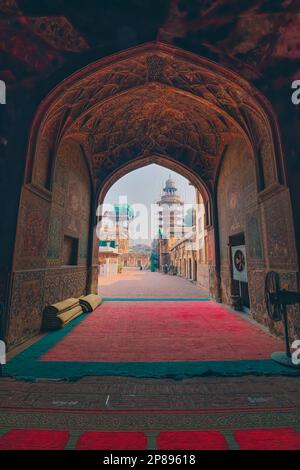 Die Bogennische am Eingang der Moschee mit Blick auf den Wazir Khan Chowk ist reich verziert mit Blumenstatuen und hat eine von Lahores Ohrmuscheln Stockfoto