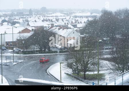 Starker Schneefall auf Basingstoke, während ein Auto durch den Kreisverkehr Victory fährt, nach einer Kältewelle am 8. März 2023. UK Stockfoto